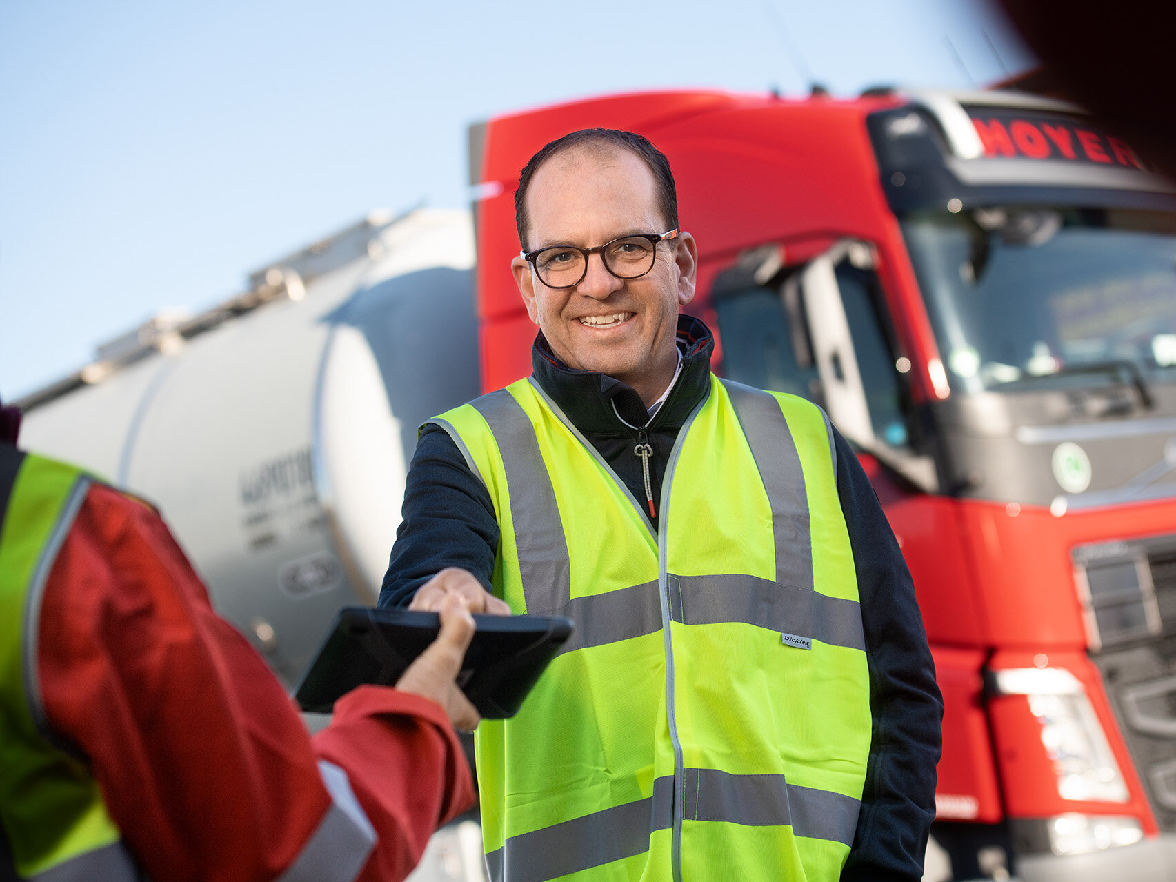 HOYER Mitarbeiter mit Warnweste und HOYER Lkw im Hintergrund