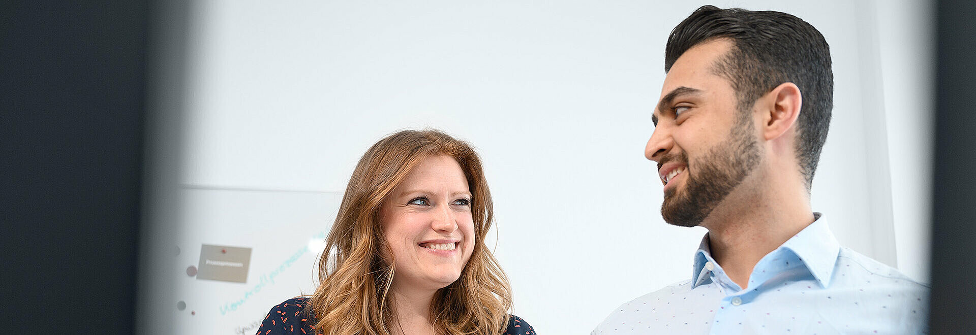 Two employees look at each other, holding a document folder