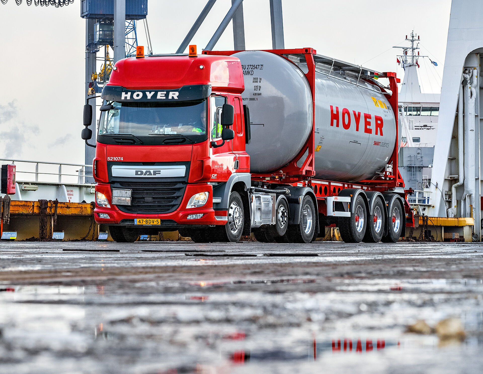 Roter LKW der HOYER Group ist mit einem Tankcontainer beladen und steht am Hafen in Rotterdam