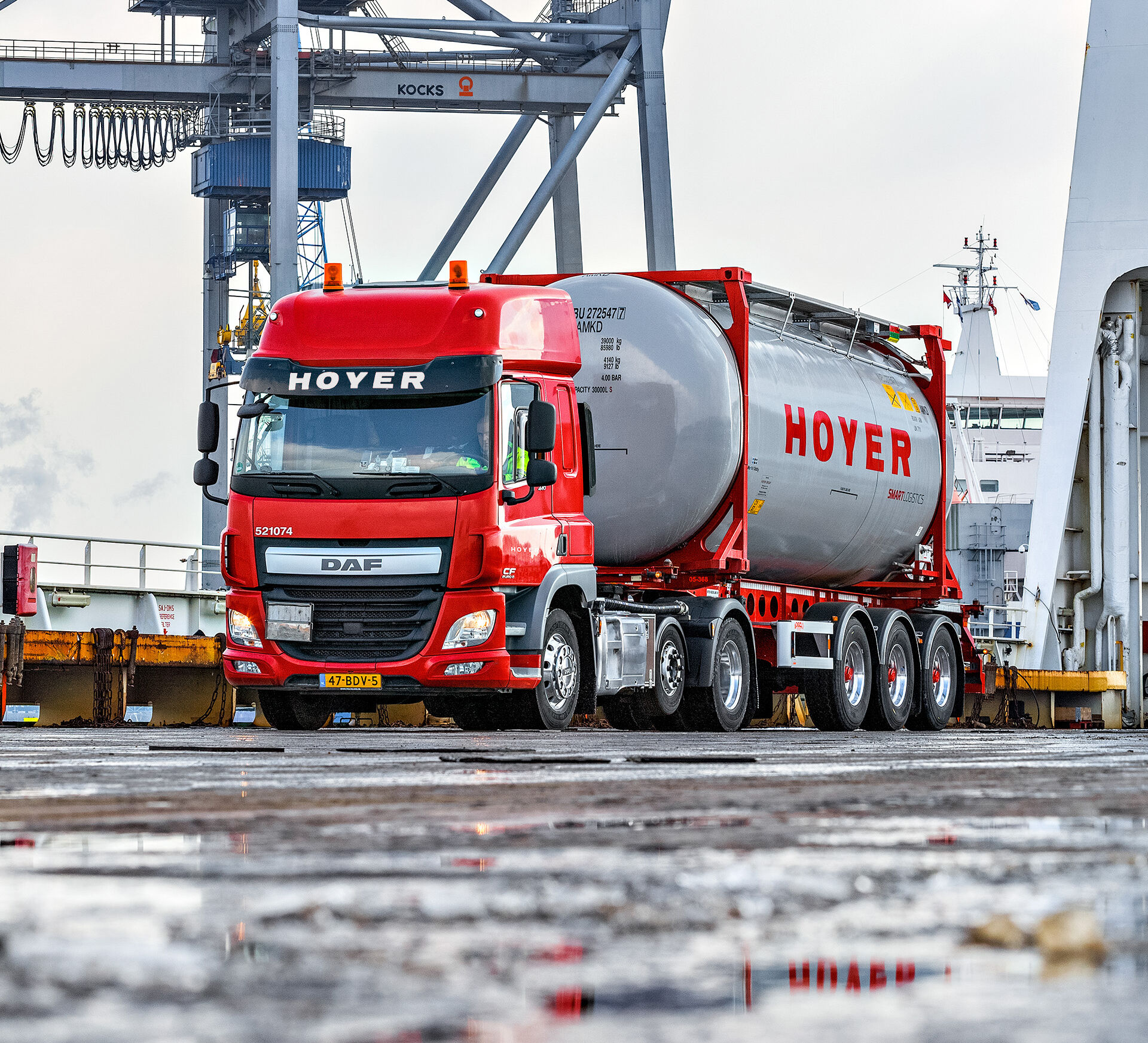 Roter LKW der HOYER Group ist mit einem Tankcontainer beladen und steht am Hafen in Rotterdam