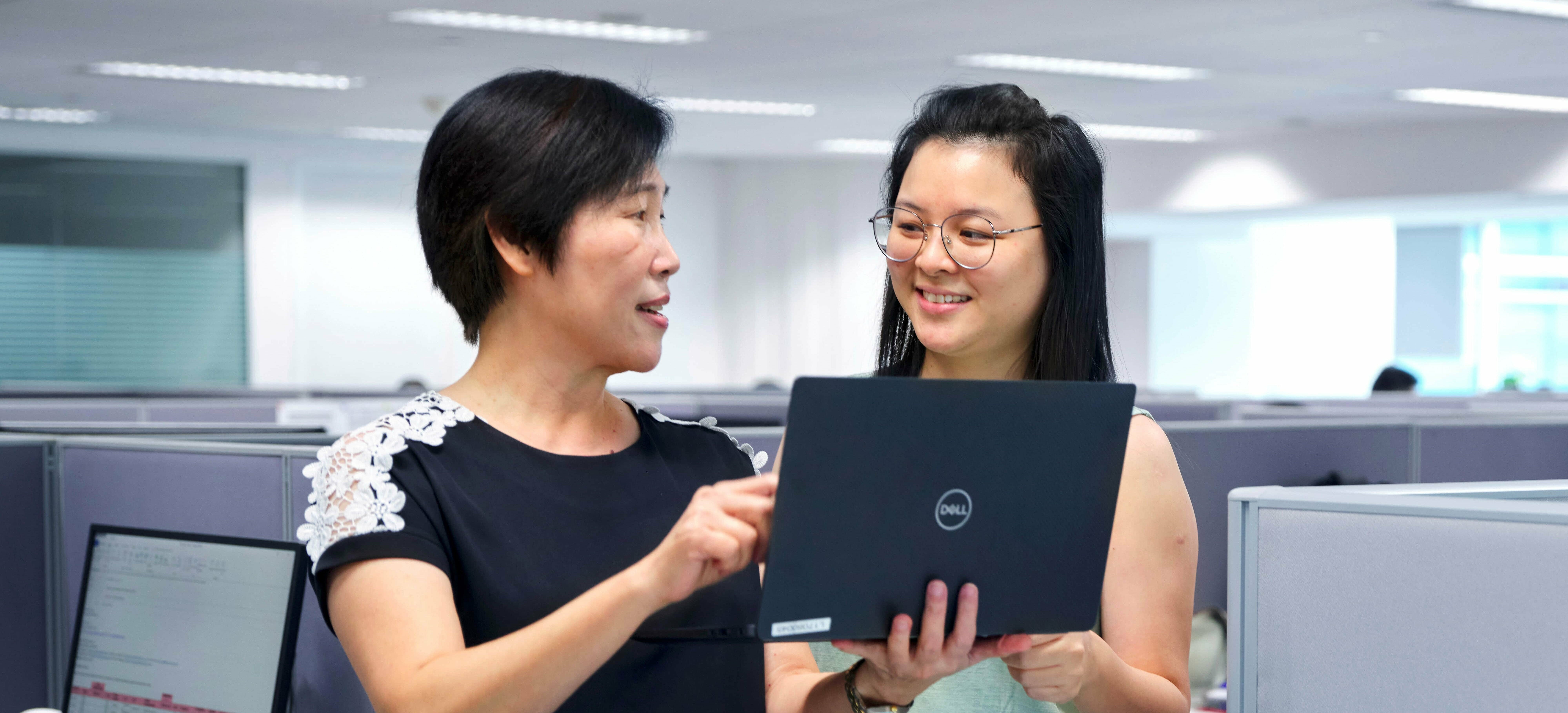 Büroangestellte halten Laptop in der Hand und planen Flexitanklogistik