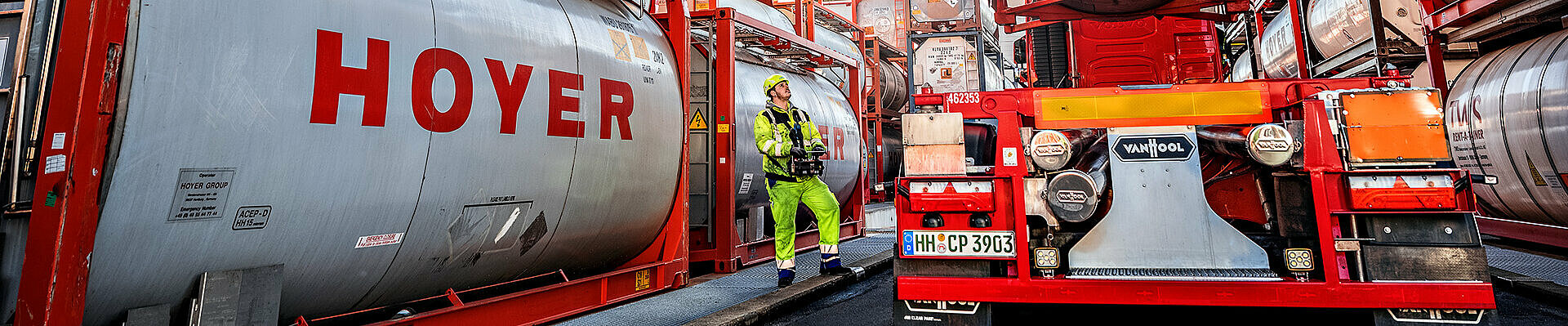 Chemical logistics HOYER tank container lifted by a crane at the hazardous goods terminal.