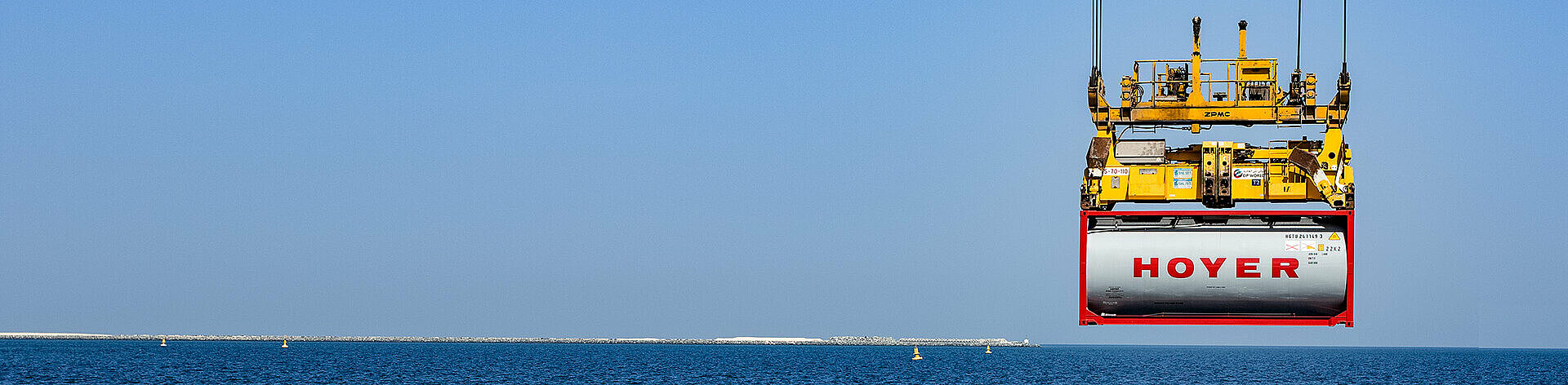 HOYER Container liftet by a crane with the ocean in the background