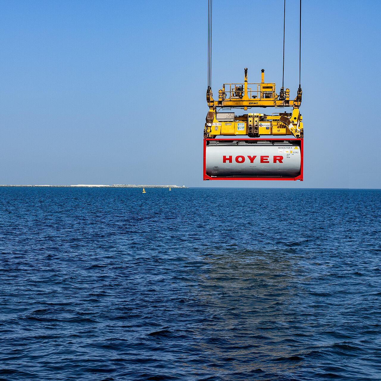 HOYER Container liftet by a crane with the ocean in the background