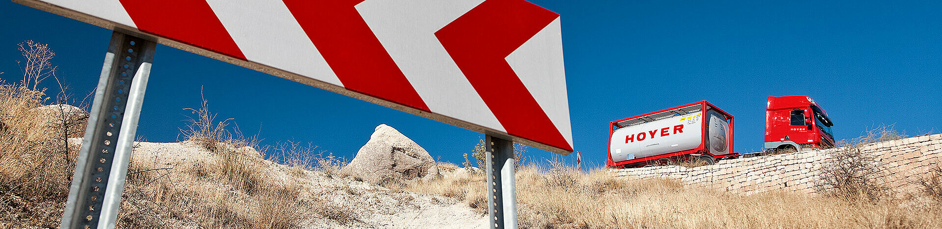 Schild und HOYER Lkw mit Chemie-Tankcontainer im Hintergrund 