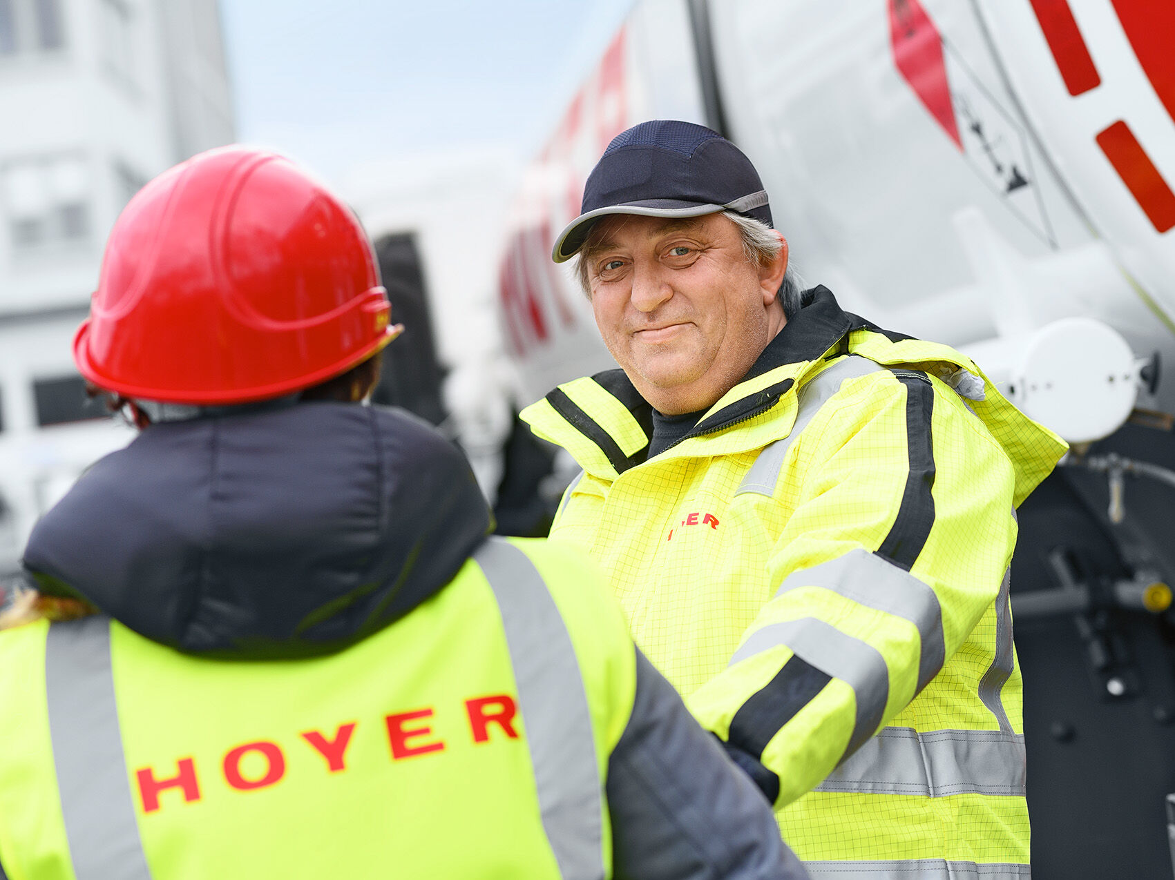 Petroleum product logistics Two HOYER employees in front of a blurry white HOYER truck