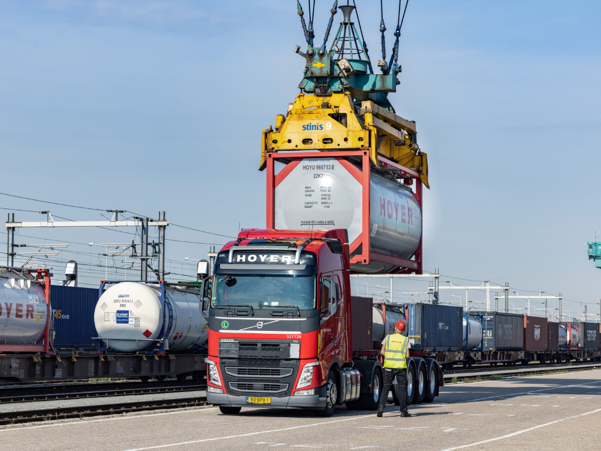 Intermodal transport HOYER Group employees in safety clothing during the loading of a chemical tank container from road to rail