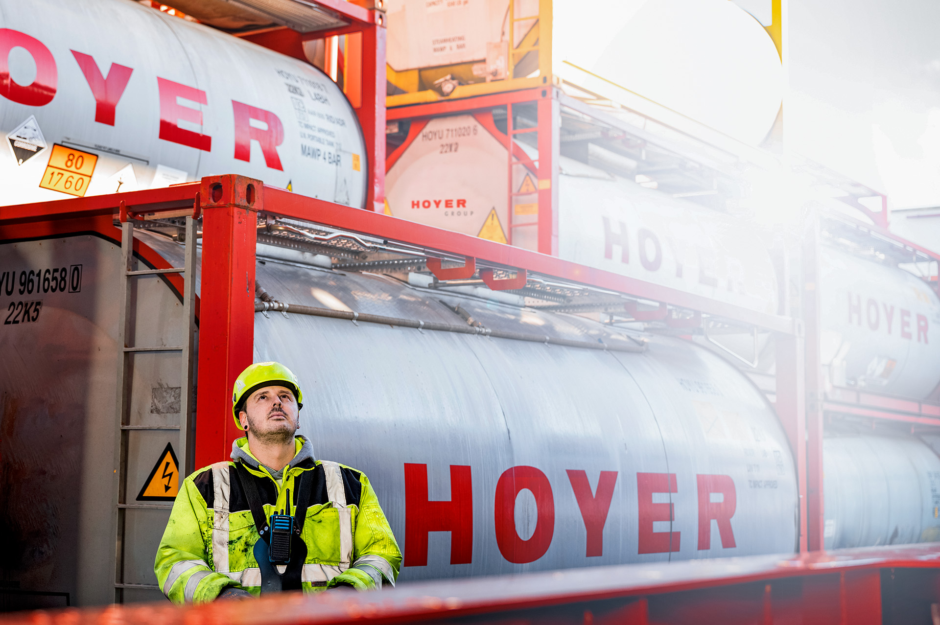 HOYER employee in front of HOYER tankcontainers, lifts tankcontainer with crane