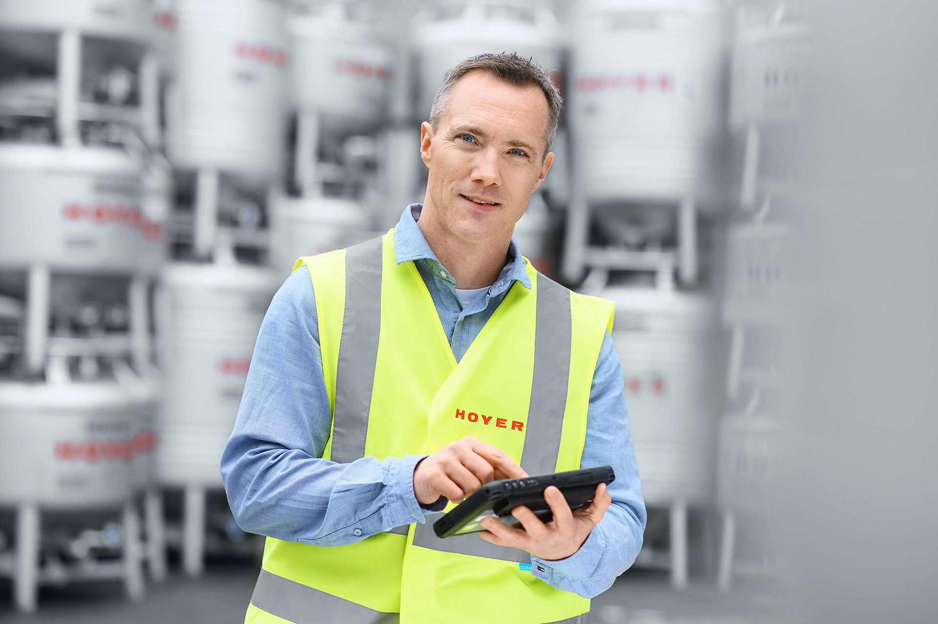 HOYER employee in a safety vest with tablet in front of IBC